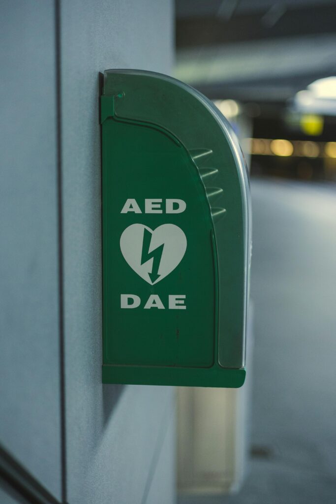 Green AED unit attached to wall indoors, vital for emergency healthcare use.